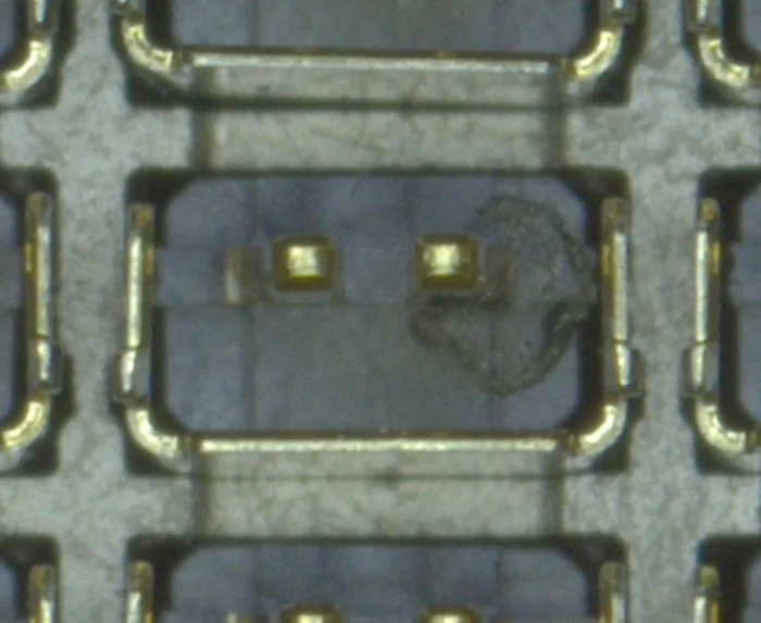 Close up of a dark speck of debris sitting between two pin cells