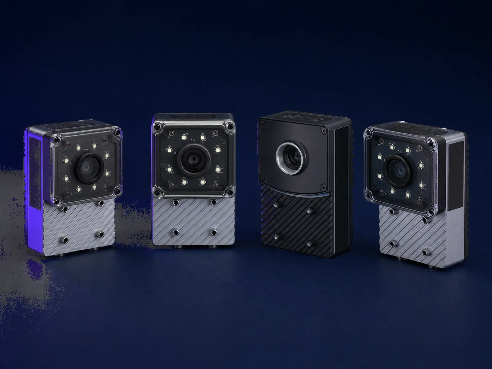 Four industrial smart cameras arranged on a dark surface, lenses and industrial connectors visible