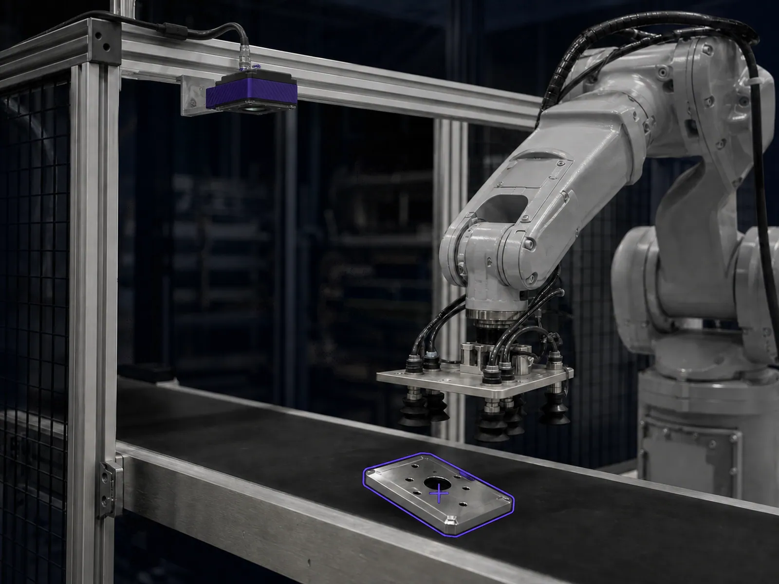 A robot arm reaching for a metal part lying at an angle, with the part outline and pick point marked